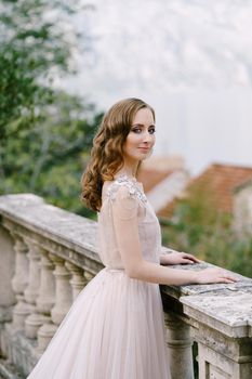 Bride stands on a stone terrace against the backdrop of the bay. High quality photo