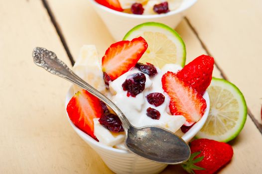 fruit and yogurt salad healthy breakfast over white wood table