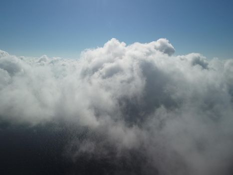 Footage B roll Aerial view drone flying above white clouds dense fog move quickly. Drone flies high back in blue sky through fluffy clouds. Beautiful foggy and cloudy slow moving Aerial view. Fog sea.