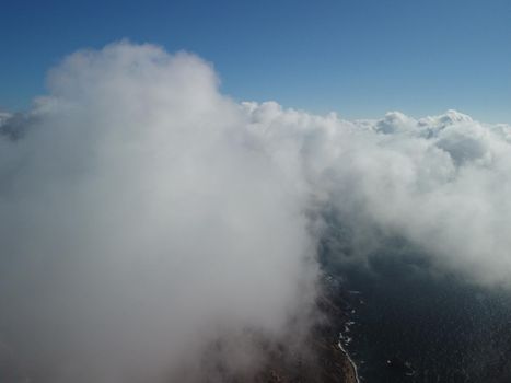 Footage B roll Aerial view drone flying above white clouds dense fog move quickly. Drone flies high back in blue sky through fluffy clouds. Beautiful foggy and cloudy slow moving Aerial view. Fog sea.