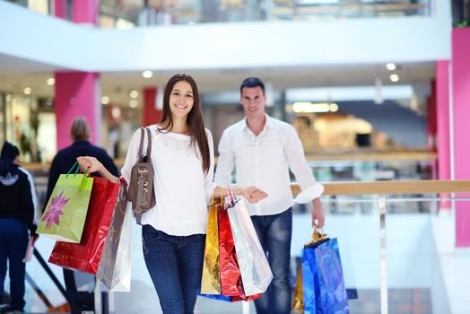 happy young couple with bags in shopping centre mall