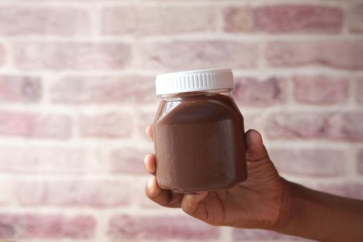 hand hold Chocolate Hazelnut cream in a container .