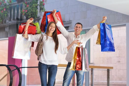 happy young couple with bags in shopping centre mall