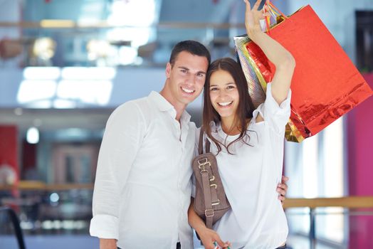 happy young couple with bags in shopping centre mall