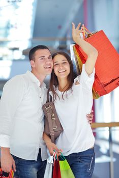 happy young couple with bags in shopping centre mall