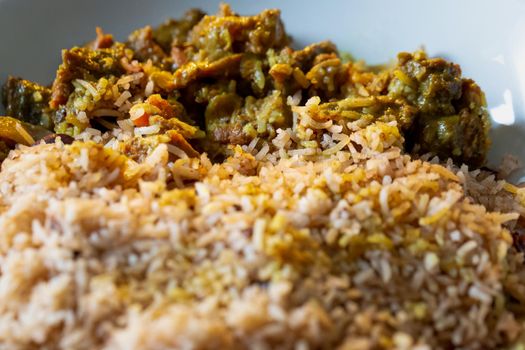 Close up of Jamaican Curried Goat served with rice and peas