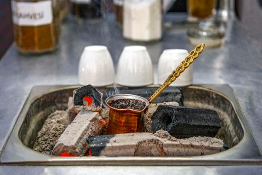 Cooking Turkish coffee on coals in a traditional way. Mobile coffee shop on the street, close-up.