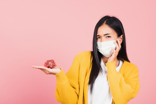 Portrait of Asian young woman wear face mask protective holding DNA strand of Coronavirus (COVID-19, 2019-ncov) genetic instruction, new strain RNA mutation, studio shot isolated on pink background