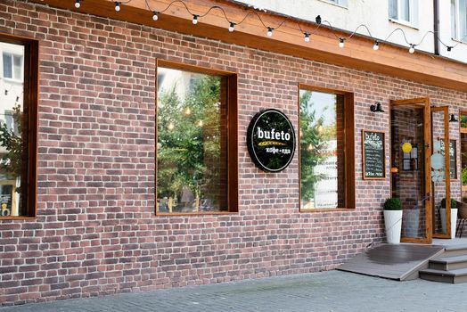 Anapa, Russia - 24 July 2021: cafe exterior with red brick wall in old town. Cafe logo on red brick wall