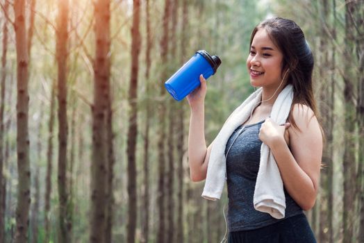 Beautiful sport young woman girl lifestyle exercise healthy drinking water after running workout in forest nature park with copy space