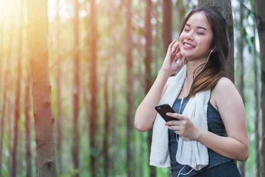 Young sport woman lifestyle using smart phone after running at forest park copy space