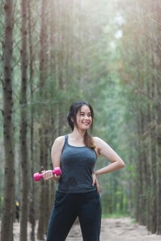Sport young woman girl lifestyle exercise holding fitness dumbbell workout in forest nature park with copy space