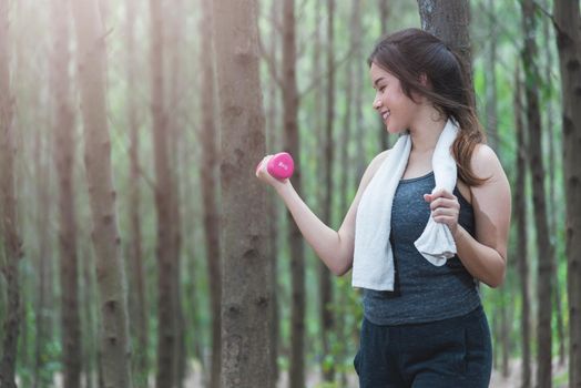 Sport young woman girl lifestyle relax holding fitness dumbbell workout in forest nature park with copy space