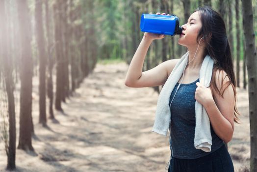 Beautiful sport young woman girl lifestyle exercise healthy drinking water after running workout in forest nature park with copy space