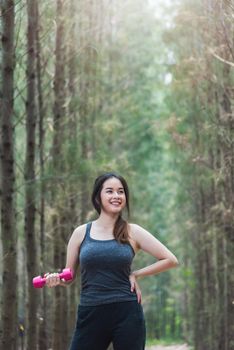 Beautiful sport young female woman lifestyle relaxation dumbbell workout in forest nature park with copy space
