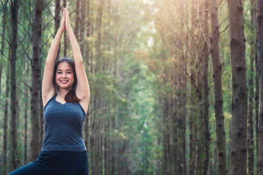 Beautiful happy young female woman relaxation standing outdoor fitness exercise yoga in forest tree nature park with copy space