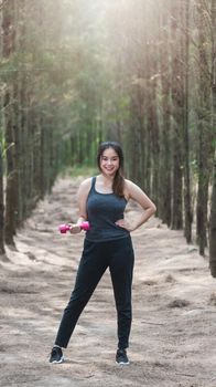 Sport young woman girl lifestyle relax holding fitness dumbbell workout in forest nature park with copy space