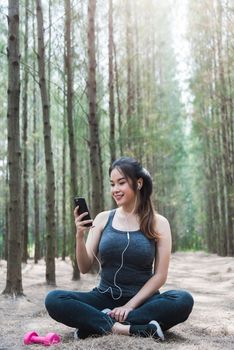 Sport happy young woman girl lifestyle exercise healthy using smart phone after dumbbell workout in forest nature park with copy space