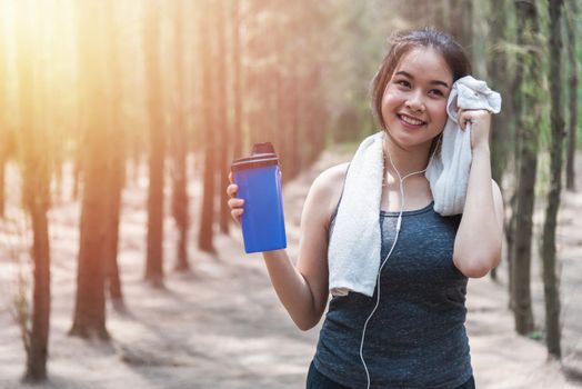 Sport beautiful young woman girl lifestyle exercise healthy drinking protein water after running workout in forest nature park with copy space