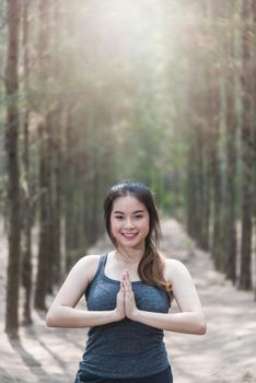 Beautiful happy young female woman relaxation standing outdoor fitness exercise yoga in forest tree nature park with copy space