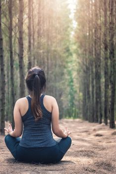 Back Beautiful young woman relaxation sitting meditation exercise yoga in morning at forest nature park