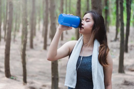 Sport beautiful young woman girl lifestyle exercise healthy drinking protein water after running workout in forest nature park with copy space