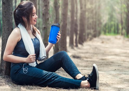 Beautiful sport young woman girl lifestyle exercise healthy drinking water from bottle after running workout in forest nature park with copy space