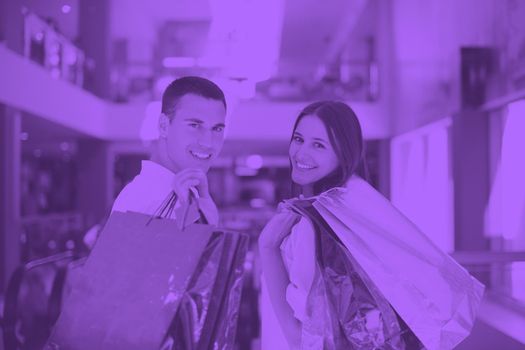 happy young couple with bags in shopping centre mall duo tone