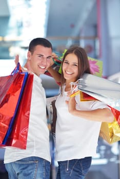 happy young couple with bags in shopping centre mall