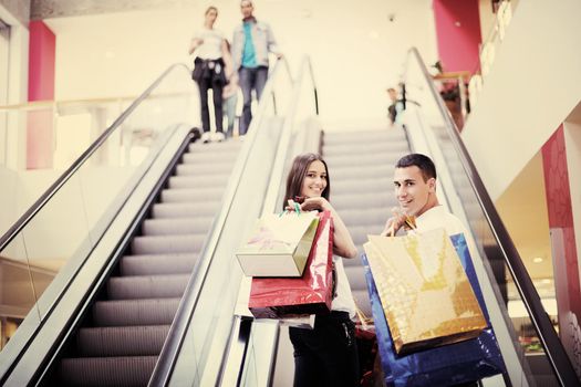 happy young couple with bags in shopping centre mall