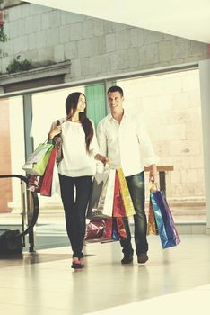 happy young couple with bags in shopping centre mall