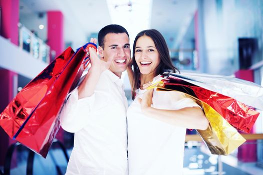 happy young couple with bags in shopping centre mall