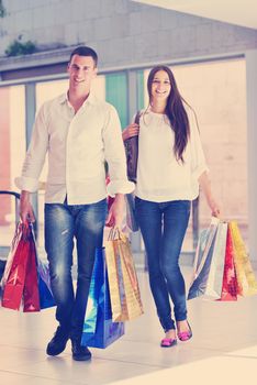 happy young couple with bags in shopping centre mall