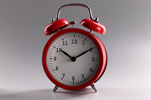 Red classic alarm clock standing on gray background closeup. Work and rest regime concept