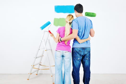 happy young couple paint in green and blue color white wall of their new home