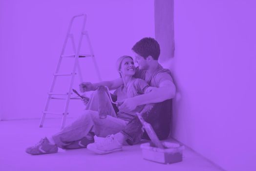 happy young couple relax after painting white wall in green and blue color in their new home duo tone