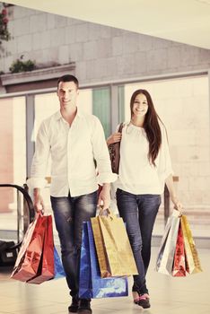 happy young couple with bags in shopping centre mall