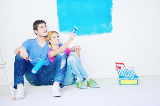 happy young couple relax after painting white wall in green and blue color in their new home