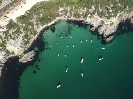 Sea landscape with rocky coastline on sunset time with cloudy sky. Yachts in the Sea on a background of rocky shores. The concept of perfect place for summer travel and rest.