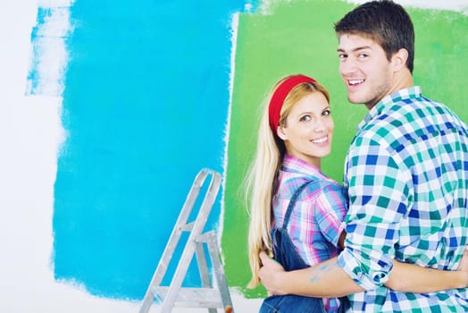 happy young couple paint in green and blue color white wall of their new home