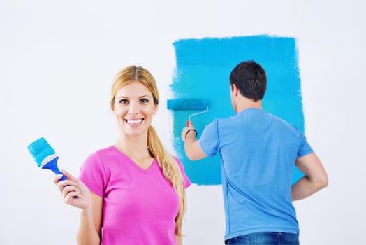 happy young couple paint in green and blue color white wall of their new home