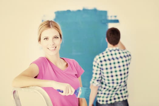 happy young couple paint in green and blue color white wall of their new home