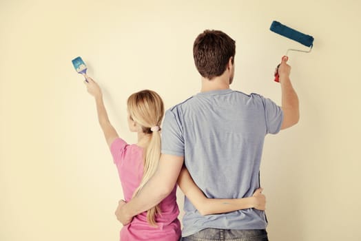 happy young couple paint in green and blue color white wall of their new home