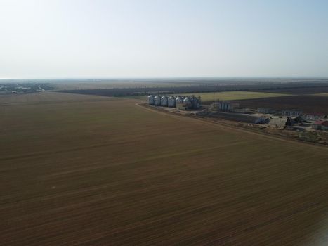 Grain elevator. Metal grain elevator in agricultural zone. Agriculture storage for harvest. Grain elevators on green nature background. Exterior of agricultural factory