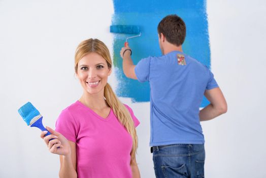 happy young couple paint in green and blue color white wall of their new home