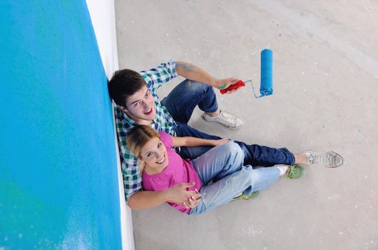 happy young couple relax after painting white wall in green and blue color in their new home