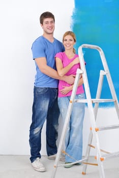 happy young couple paint in green and blue color white wall of their new home