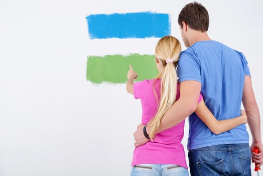 happy young couple paint in green and blue color white wall of their new home