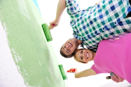 happy young couple paint in green and blue color white wall of their new home