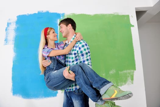 happy young couple paint in green and blue color white wall of their new home